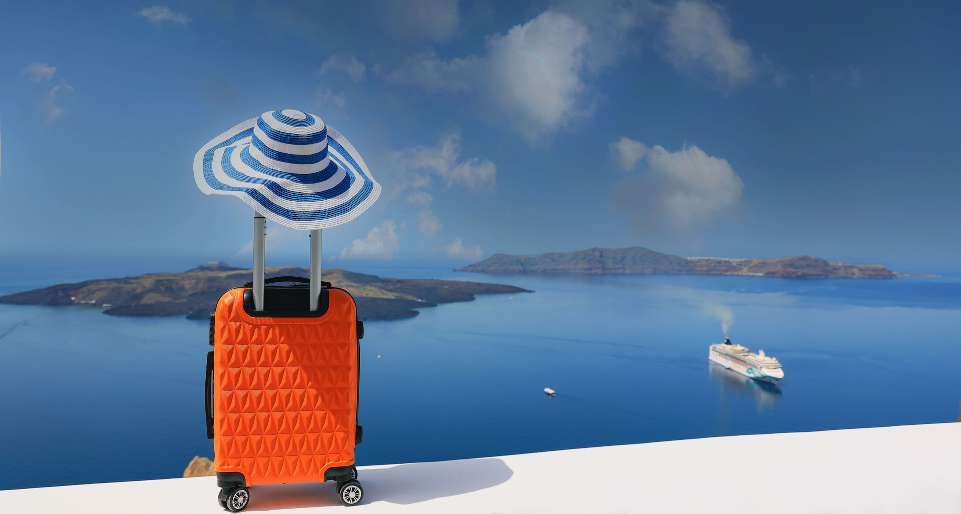 Blue trend with banner of travel concept with Orange luggage with hat and landscape view of Oia town in Santorini island in Greece , Greek landscape as blue sky background